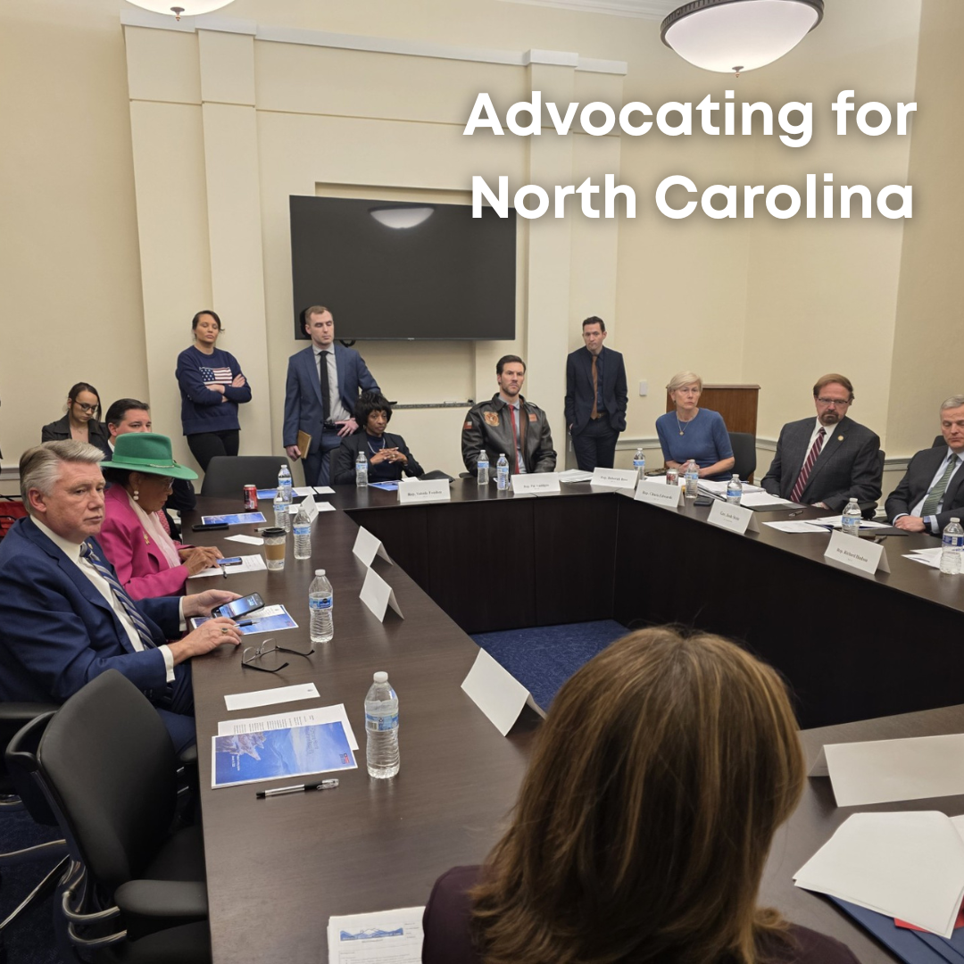 Rep. Adams sits at a table with Gov. Stein, other members of Congress