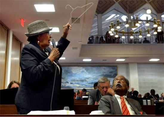 Rep. Adams holding coat hanger of the floor of NC House